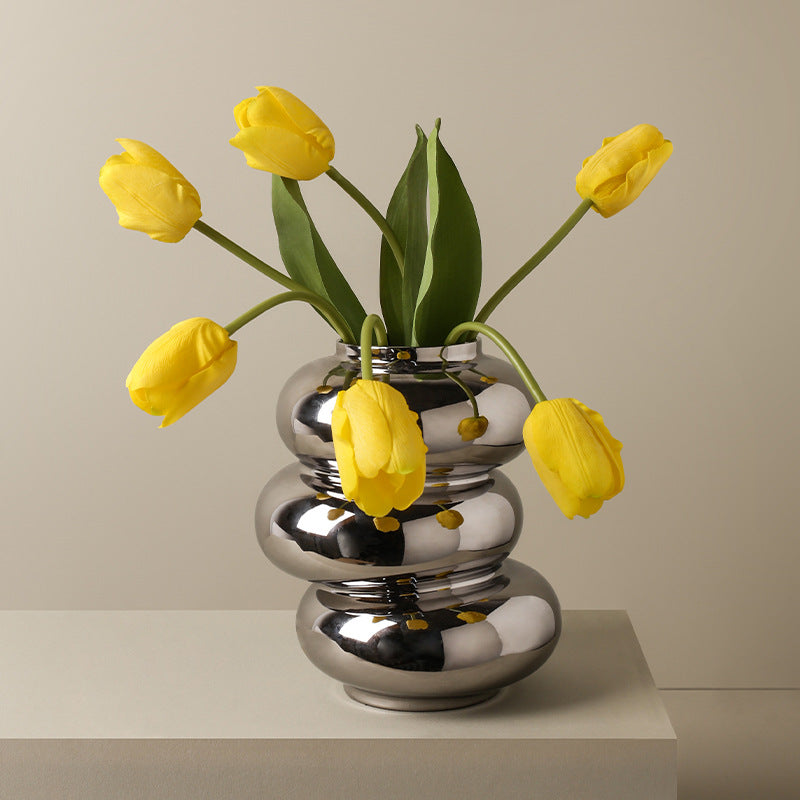 Triple Stack Orb Vase, reflective chrome-finish ceramic with rounded tiered form holding bright yellow tulips