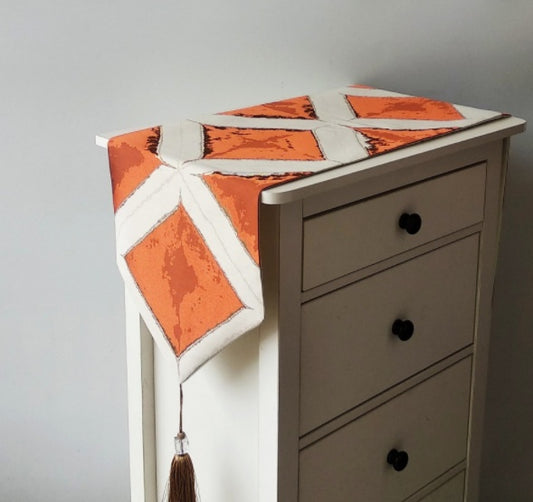 Geometric Patchwork Table Runner, cream fabric with bold orange panels and white intersecting lines with tassel detail