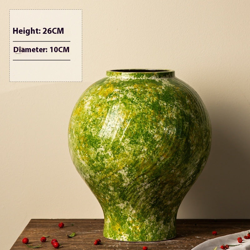 Green ceramic vase on a wooden surface with a beige background