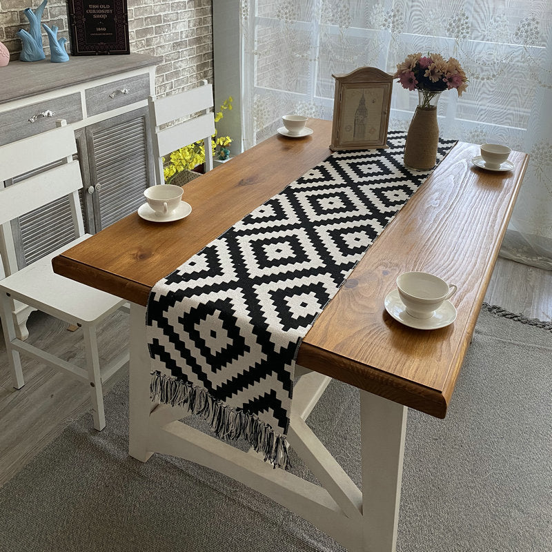 Geometric Diamond Table Runner, black and white woven fabric with bold diamond pattern and tasseled edges