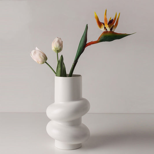 Sculptural Twist Vase, matte white ceramic with stacked curved form holding tulips and bird of paradise stems