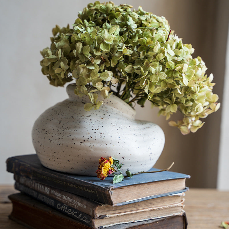 Speckled Pebble Vase, off-white stoneware with organic low-profile form holding dried green hydrangea blooms