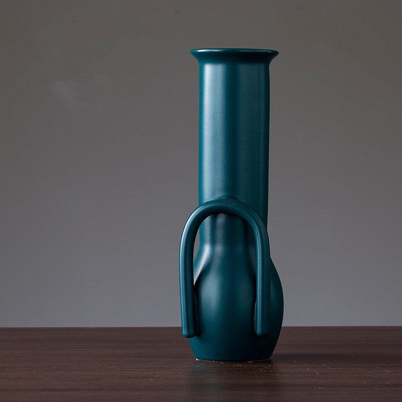 Teal vase with a handle on a wooden surface and gray background