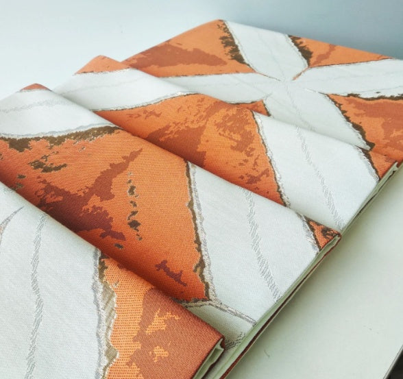 Geometric Patchwork Table Runner, cream fabric with bold orange panels and textured angular pattern
