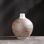 Round squat ceramic vase with fine red-brown horizontal stripe texture on dark grey background
