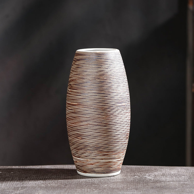 Oval hand-textured ceramic vase with fine horizontal line pattern on dark grey background