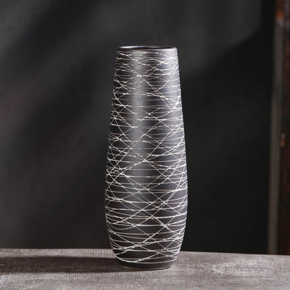 Tall black and white patterned vase on a dark background