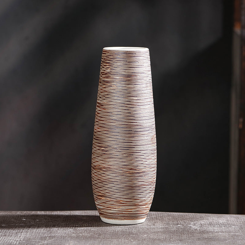 Tall slim hand-textured ceramic vase with fine line striped pattern on dark moody background