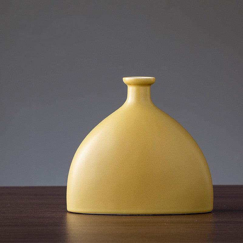 Yellow ceramic vase on a wooden surface with a gray background