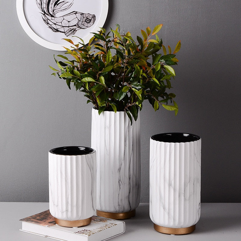 Fluted Marble Vase Set, white marble with vertical ribbed texture and wood base accents styled with lush greenery