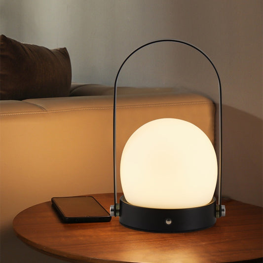 Modern Arc Table Lamp, frosted dome glass shade with black metal handle frame and warm ambient glow