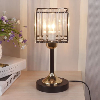 Crystal Square Table Lamp, clear faceted glass shade with black and gold metal base and warm ambient glow