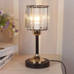 Crystal Column Table Lamp, clear ribbed glass shade with black and gold metal base and warm glowing light