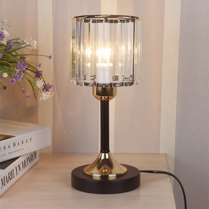 Crystal Column Table Lamp, clear ribbed glass shade with black and gold metal base and warm glowing light