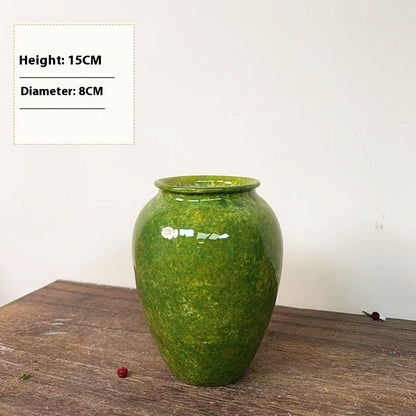 Green ceramic vase on a wooden surface with measurements displayed.